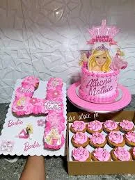 Pink Barbie themed birthday cake with a large Barbie printout topper and matching pink cupcakes arranged in the shape of the number four.