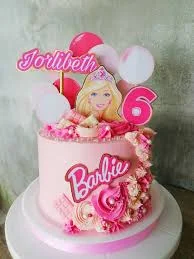 Pink Barbie themed birthday cake with a Barbie printout topper, pink icing rosettes, and a custom name banner.