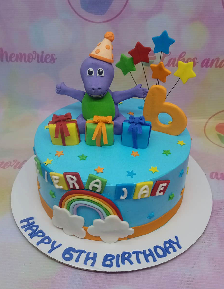 Blue Barney themed birthday cake with a 3D Barney figure, fondant gifts, a rainbow, and colorful stars. Blue Barney themed birthday cake with a 3D Barney figure, fondant gifts, a rainbow, and colorful stars.