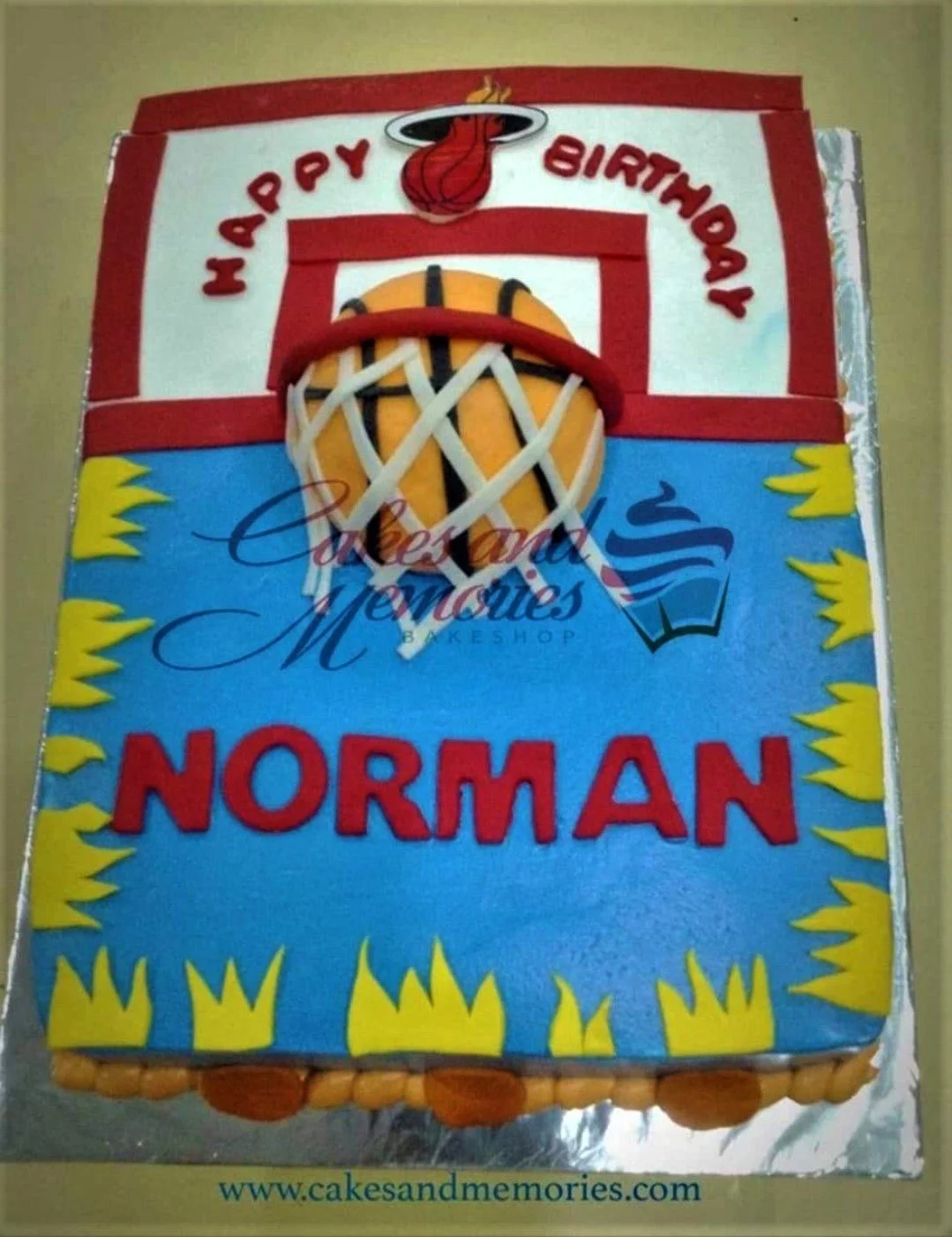 Miami Heat basketball themed rectangle cake with a 3D basketball hoop and ball, yellow flames, and red lettering.