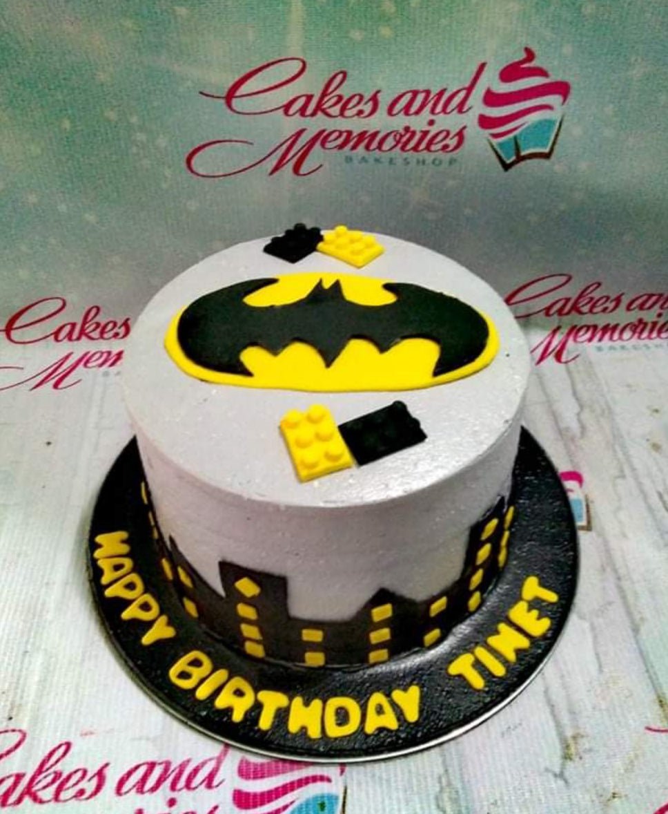 Batman themed birthday cake with yellow and black Lego brick accents and a city skyline silhouette. Batman themed birthday cake with yellow and black Lego brick accents and a city skyline silhouette.
