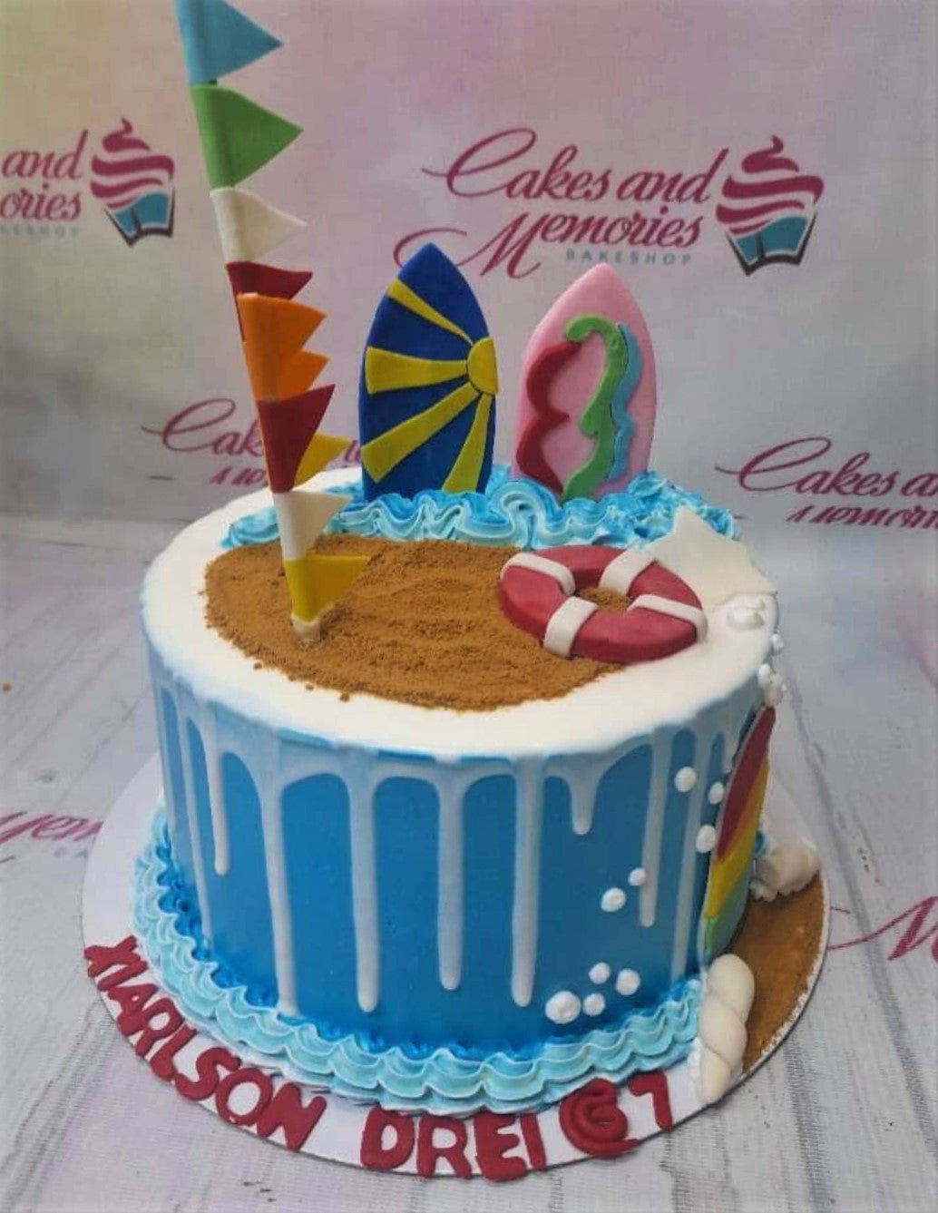 Blue beach themed cake with surfboards, lifebuoy, and sand decorations for a birthday celebration. Blue beach themed cake with surfboards, lifebuoy, and sand decorations for a birthday celebration.