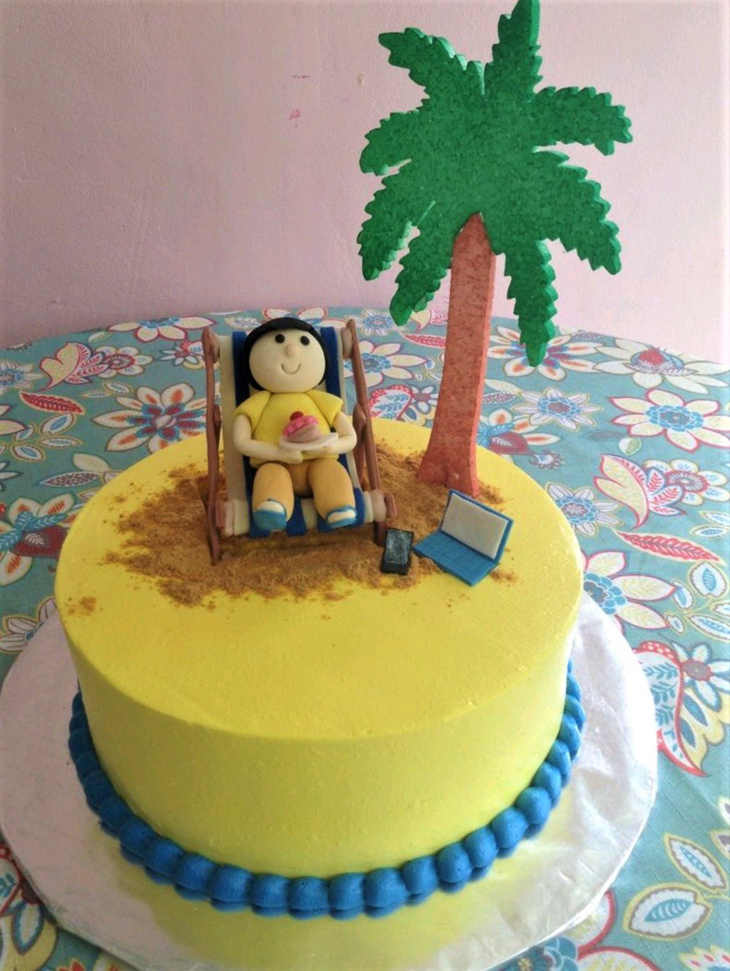 Yellow beach themed cake with a fondant person relaxing on a lounge chair under a palm tree with a laptop and phone. Yellow beach themed cake with a fondant person relaxing on a lounge chair under a palm tree with a laptop and phone.