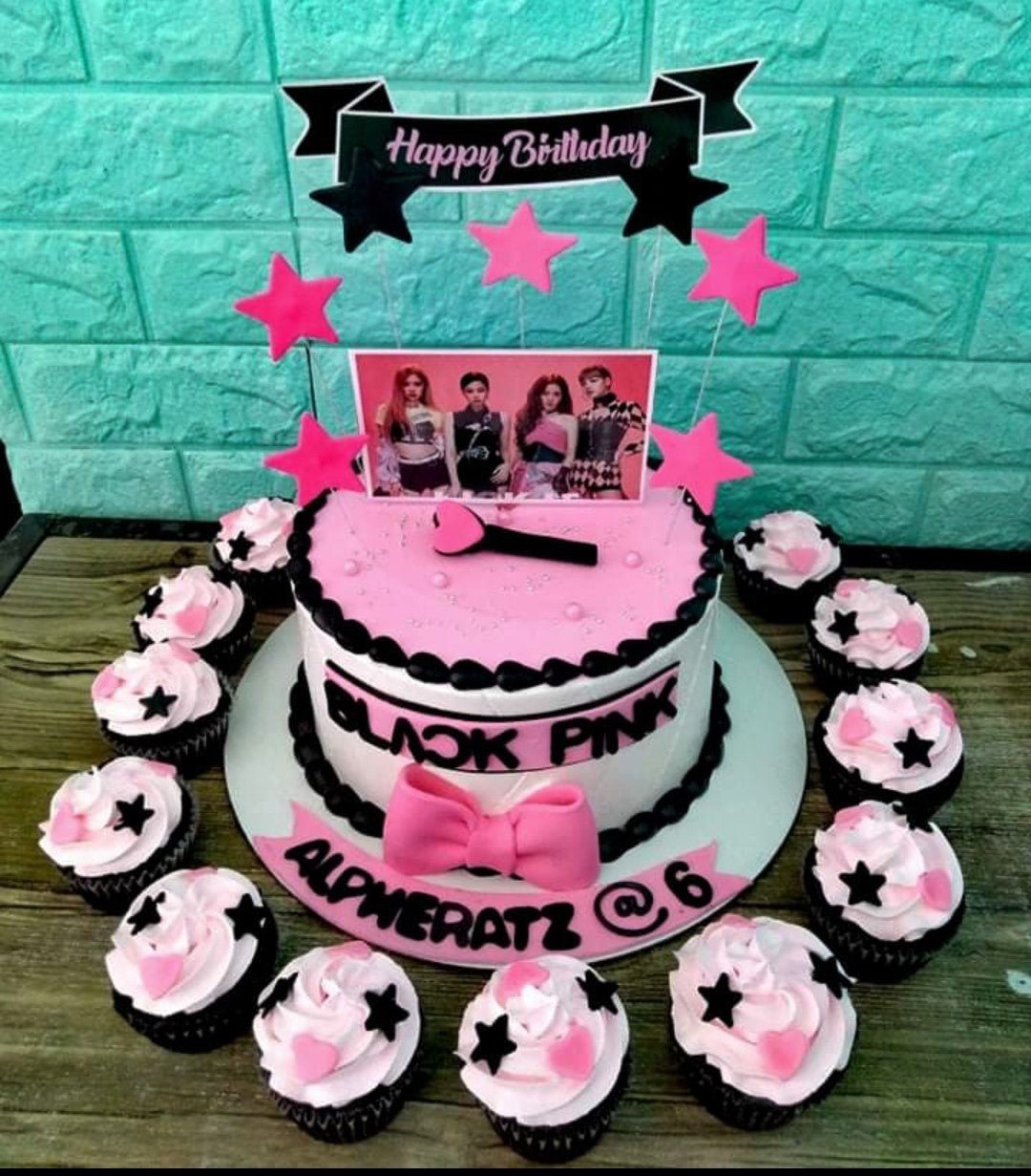 Blackpink themed birthday cake with pink icing, black borders, character printouts, and matching cupcakes. Blackpink themed birthday cake with pink icing, black borders, character printouts, and matching cupcakes.