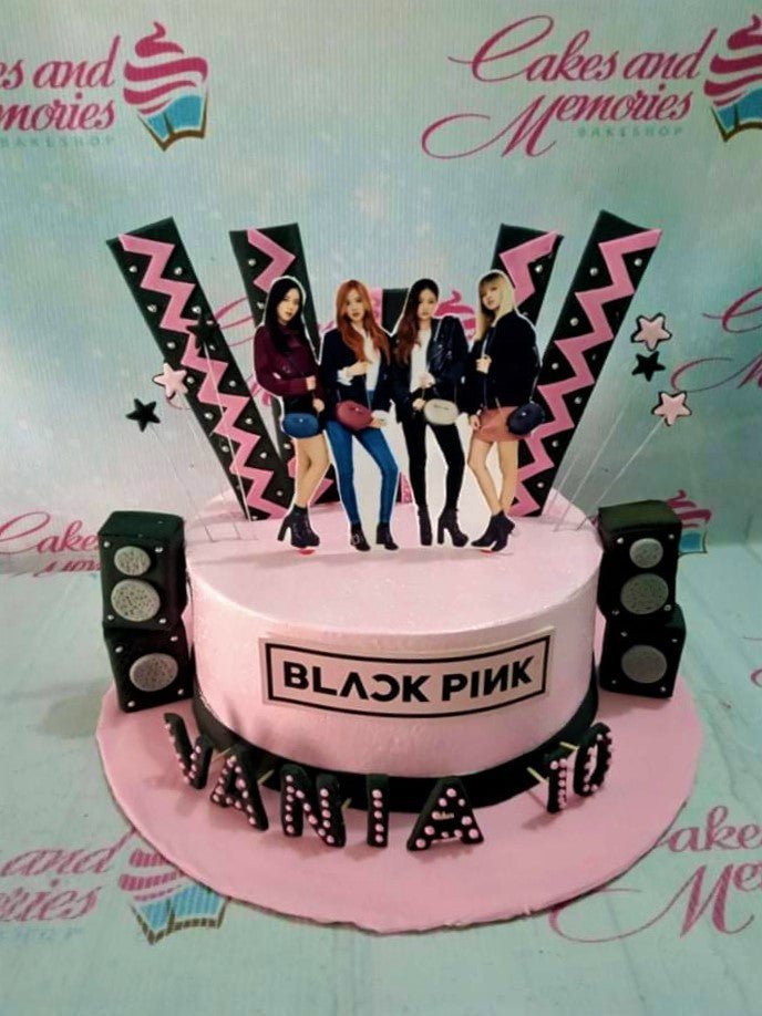 Pink Blackpink themed birthday cake with character printouts, speaker decorations, and a Blackpink logo. Pink Blackpink themed birthday cake with character printouts, speaker decorations, and a Blackpink logo.