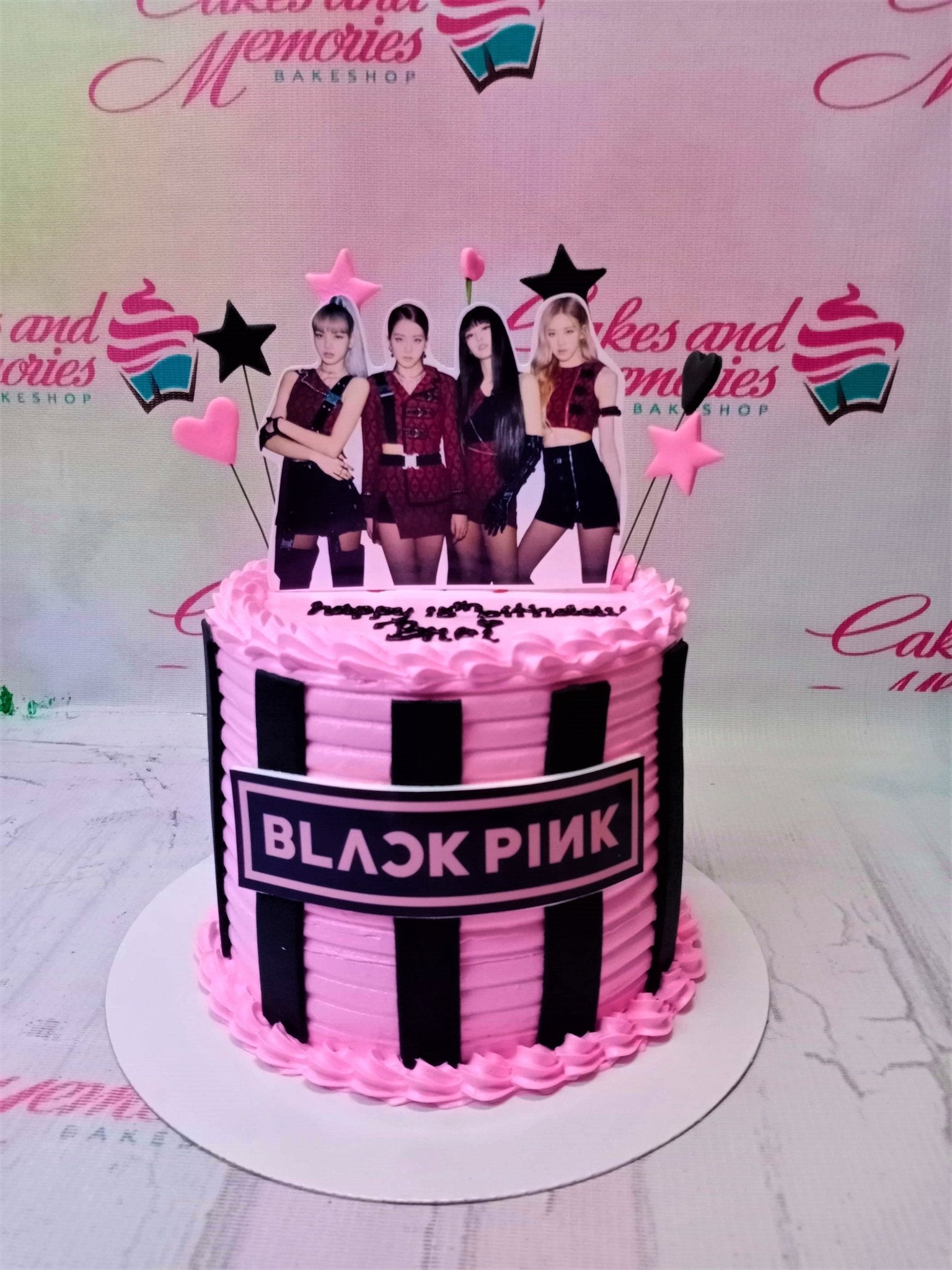 Pink Blackpink themed birthday cake with vertical black stripes and character printouts of the K-pop group members. Pink Blackpink themed birthday cake with vertical black stripes and character printouts of the K-pop group members.