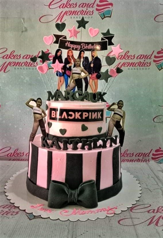 Pink and black 2-tier Blackpink themed birthday cake with character printouts, stars, hearts, and a large black bow. Pink and black 2-tier Blackpink themed birthday cake with character printouts, stars, hearts, and a large black bow.