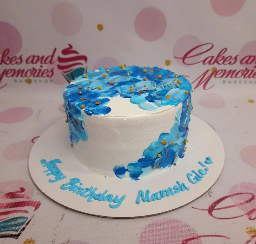 Blue Minimalist Cake A white and blue 1-tier cake themed Blue Minimalist, featuring blue palette knife icing strokes, gold dragees, and blue text.