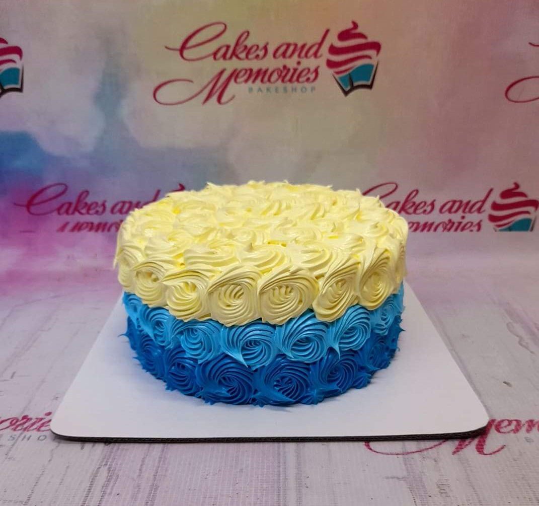 Single tier cake covered in blue and yellow icing rosettes creating a gradient effect from dark blue to light yellow. Single tier cake covered in blue and yellow icing rosettes creating a gradient effect from dark blue to light yellow.