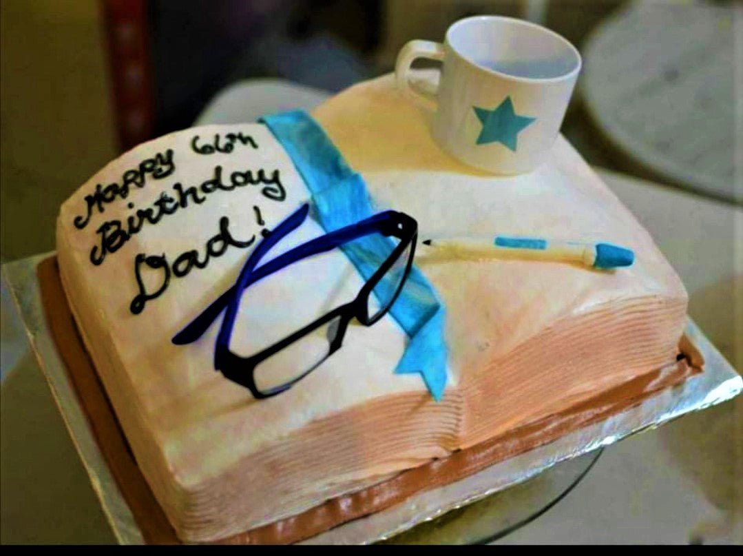 Square book-shaped cake for a 66th birthday with fondant glasses, a coffee mug, and a pen topper. Square book-shaped cake for a 66th birthday with fondant glasses, a coffee mug, and a pen topper.