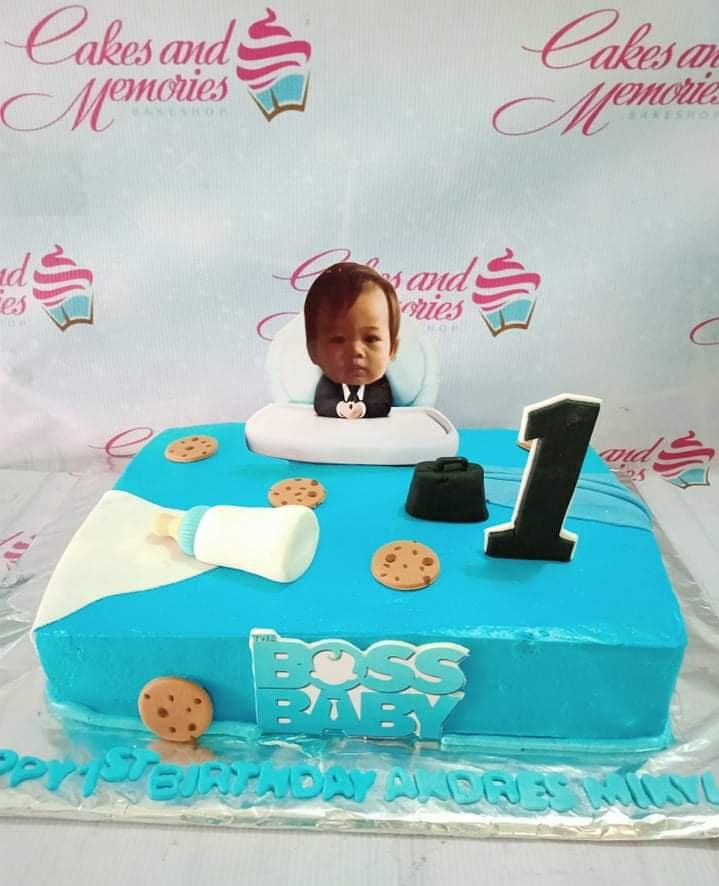 Blue Boss Baby themed rectangle cake with a photo printout of a baby, fondant cookies, and a black briefcase topper. Blue Boss Baby themed rectangle cake with a photo printout of a baby, fondant cookies, and a black briefcase topper.