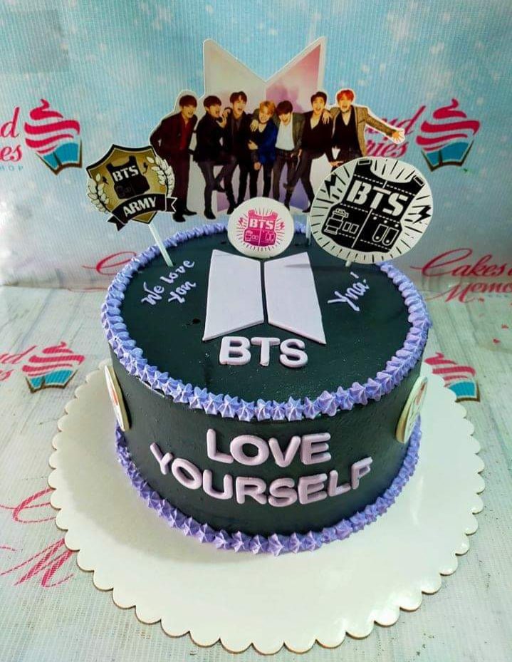 Black BTS themed birthday cake with purple icing borders and K-pop group member printout toppers. Black BTS themed birthday cake with purple icing borders and K-pop group member printout toppers.