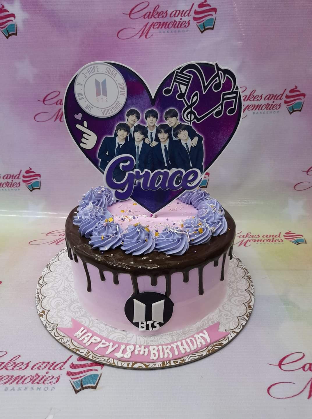 Purple BTS themed birthday cake with a large heart-shaped printout topper, chocolate drip, and lavender icing rosettes. Purple BTS themed birthday cake with a large heart-shaped printout topper, chocolate drip, and lavender icing rosettes.