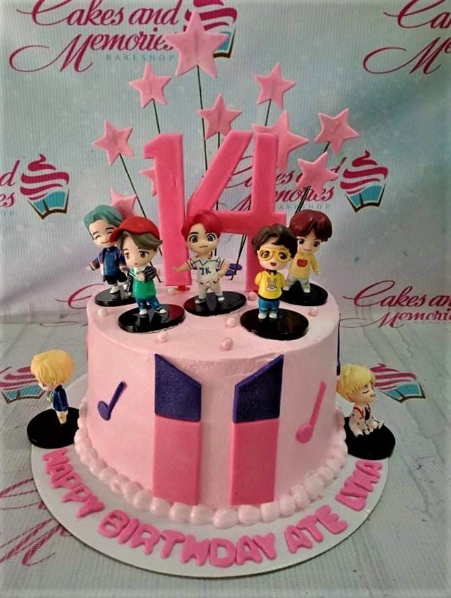 Pink BTS themed birthday cake with 3D character figurines, pink stars on wires, and a large number 14 topper. Pink BTS themed birthday cake with 3D character figurines, pink stars on wires, and a large number 14 topper.