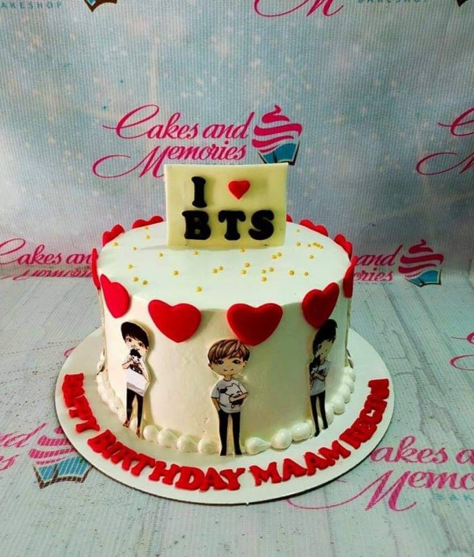 White BTS themed birthday cake with red fondant hearts, gold sprinkles, and printed character toppers of the band members. White BTS themed birthday cake with red fondant hearts, gold sprinkles, and printed character toppers of the band members.