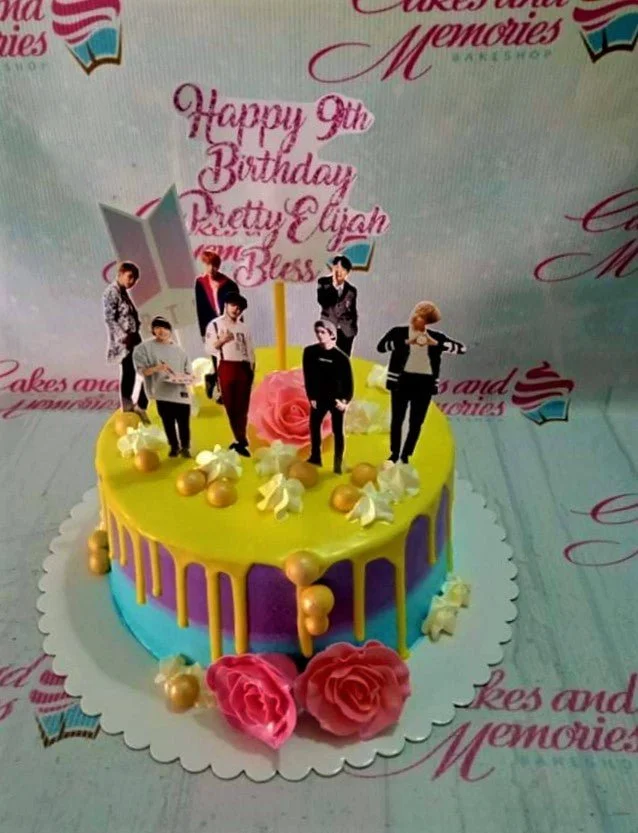 BTS Kpop-Inspired Orange Drip Birthday Cake BTS K-pop themed birthday cake with yellow drip icing, purple and blue gradient base, and printed character toppers.