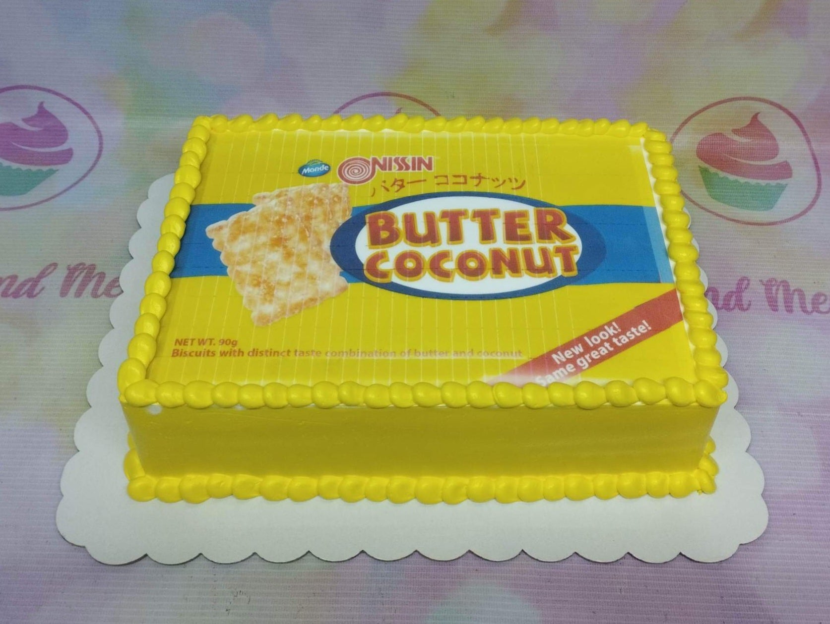 Yellow rectangle cake designed to look like a Nissin Butter Coconut biscuit pack with yellow piped icing borders. Yellow rectangle cake designed to look like a Nissin Butter Coconut biscuit pack with yellow piped icing borders.