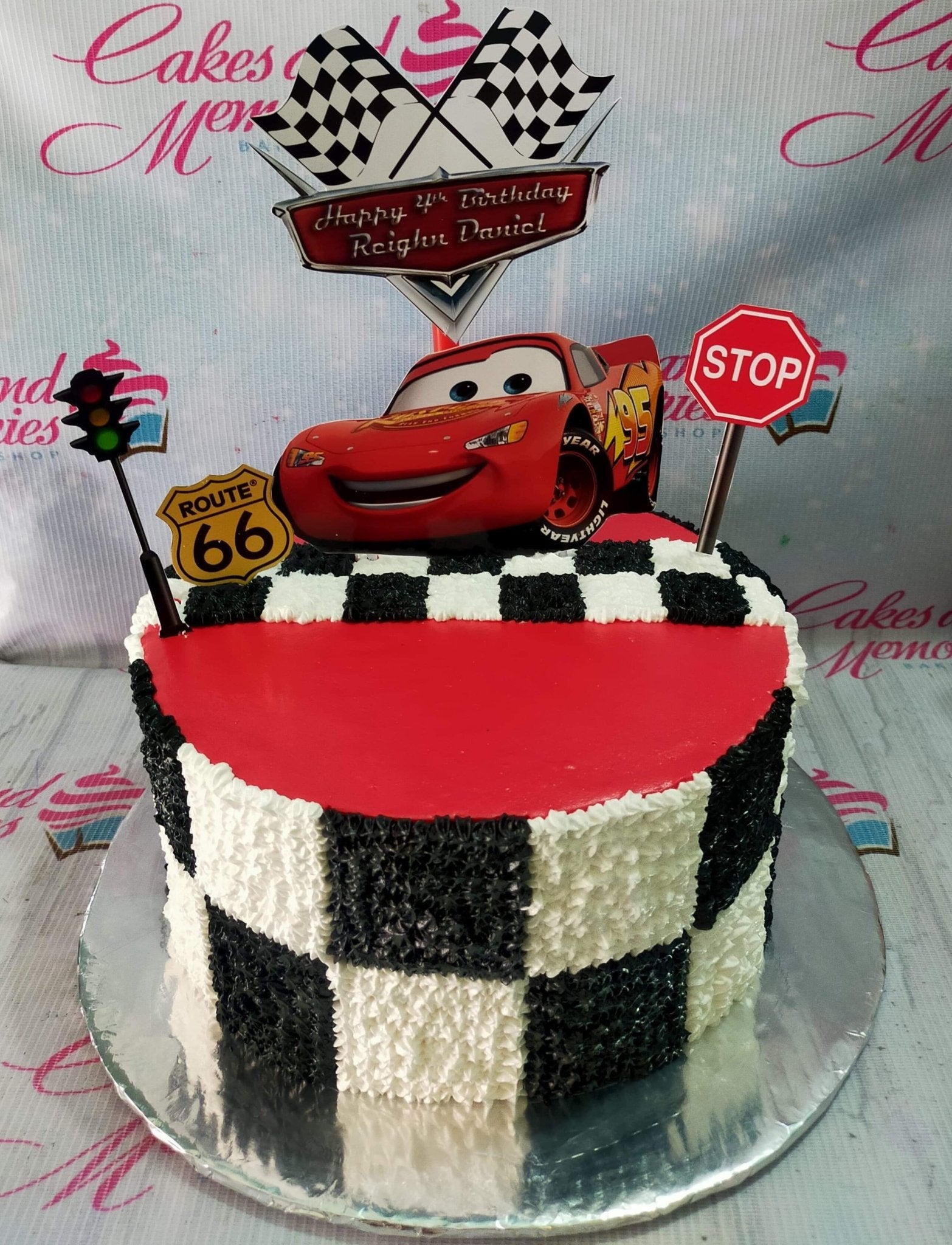 Disney Cars Lightning McQueen themed birthday cake with red icing and black and white checkered pattern on the sides. Disney Cars Lightning McQueen themed birthday cake with red icing and black and white checkered pattern on the sides.