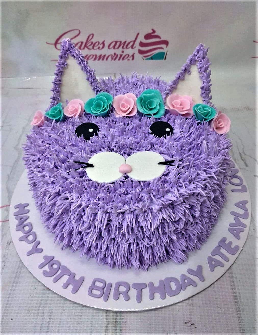 Purple cat-shaped birthday cake with pink and teal icing roses and a purple message on the base board. Purple cat-shaped birthday cake with pink and teal icing roses and a purple message on the base board.