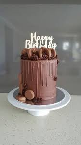 A brown 6-inch cake featuring a chocolate drip, a 'Happy Birthday' topper, chocolate biscuits, and chocolate buttercream swirls. A brown 6-inch cake featuring a chocolate drip, a 'Happy Birthday' topper, chocolate biscuits, and chocolate buttercream swirls.
