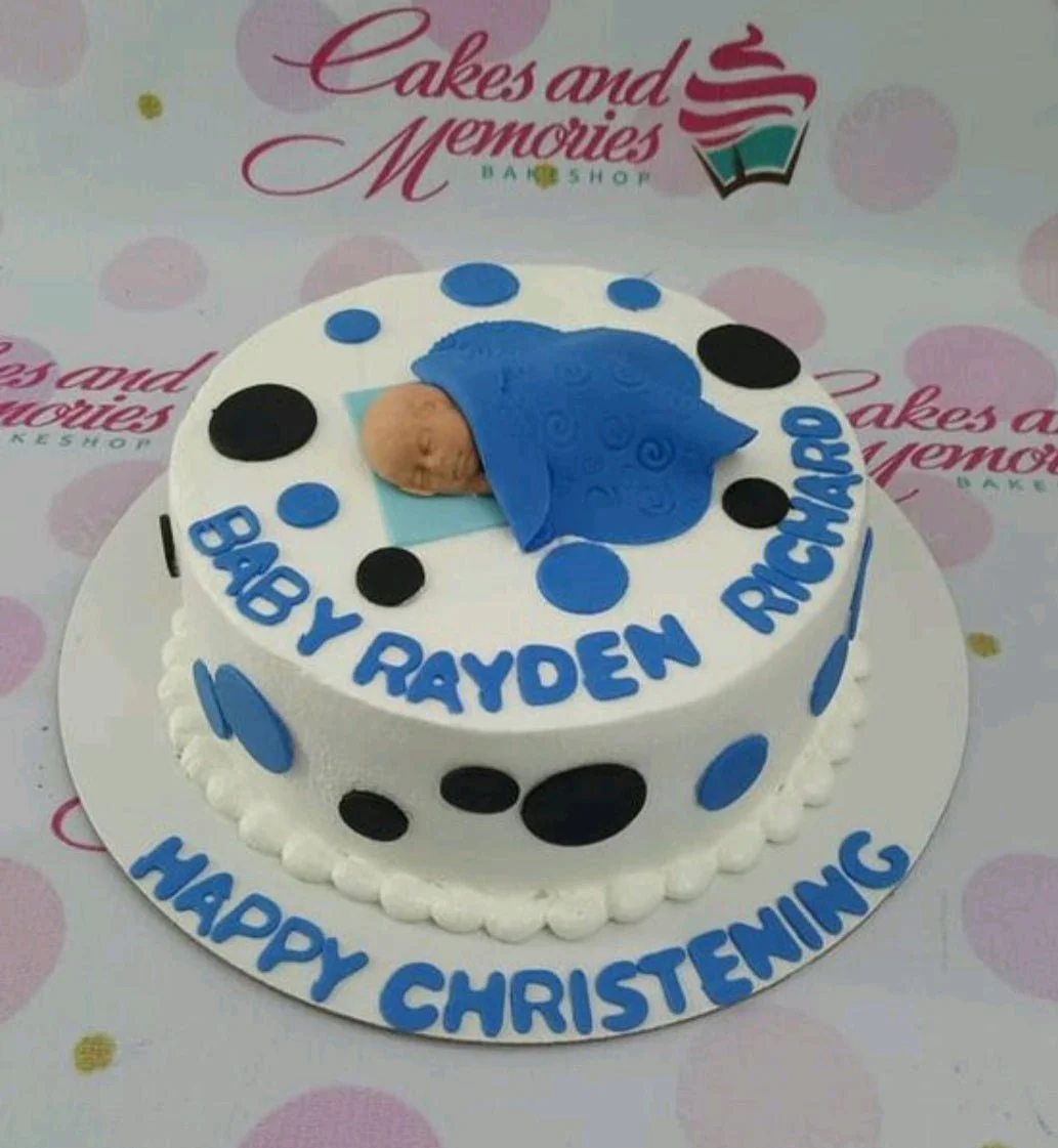 Christening White Cake White round christening cake with a blue fondant sleeping baby topper and blue and black polka dots.