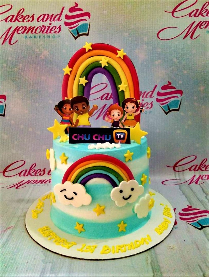 ChuChu TV themed birthday cake with rainbows, clouds, and character printouts on a light blue and white gradient icing base. ChuChu TV themed birthday cake with rainbows, clouds, and character printouts on a light blue and white gradient icing base.