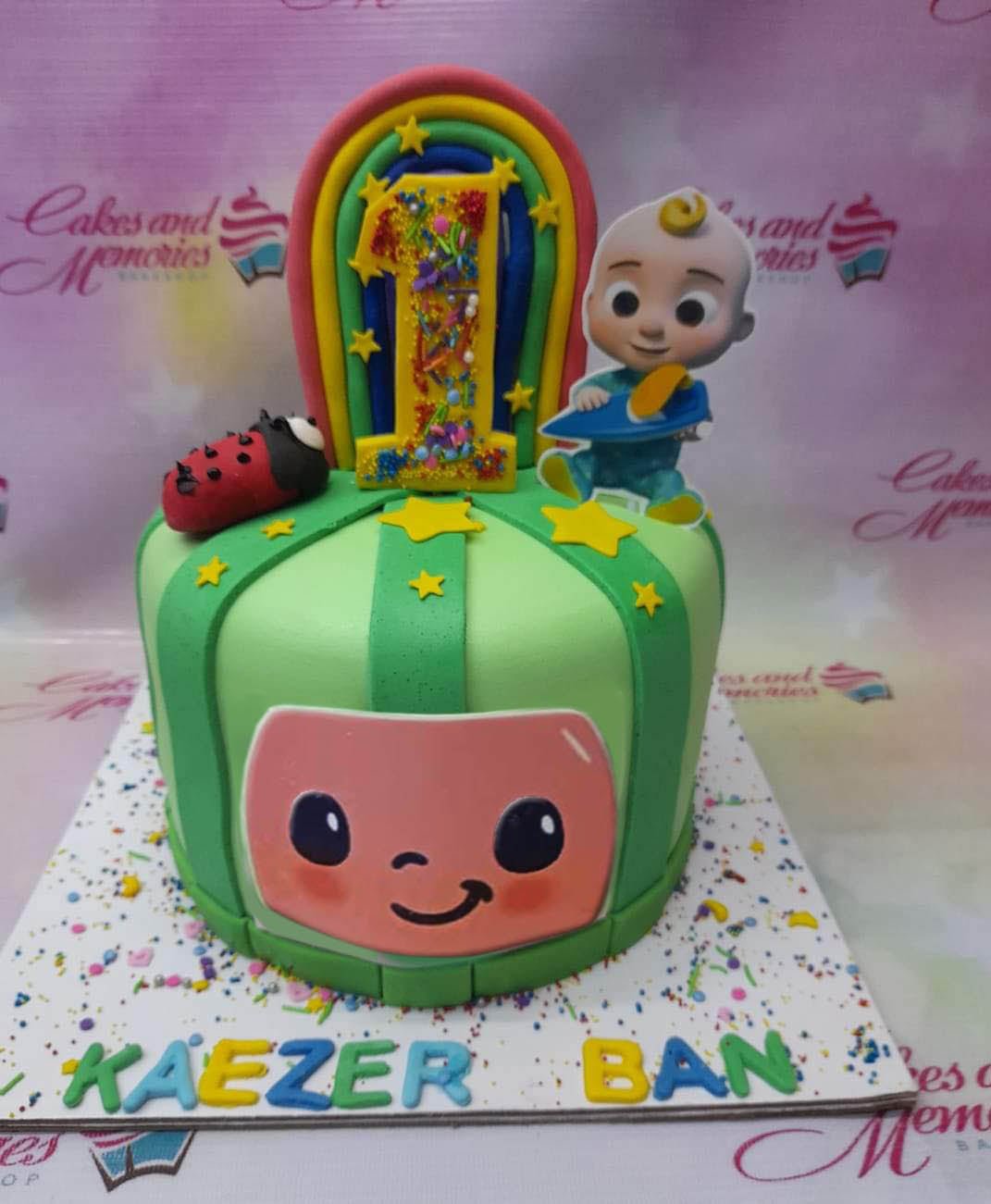 Cocomelon themed green fondant cake with a rainbow, ladybug, and character printouts for a first birthday celebration. Cocomelon themed green fondant cake with a rainbow, ladybug, and character printouts for a first birthday celebration.