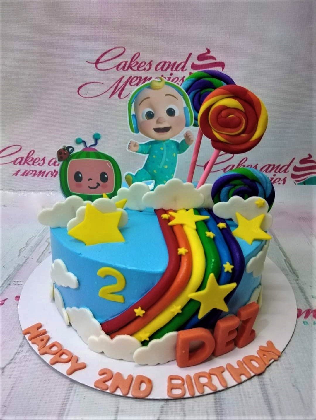 Light blue Cocomelon birthday cake with a rainbow, JJ printout topper, and fondant clouds and stars. Light blue Cocomelon birthday cake with a rainbow, JJ printout topper, and fondant clouds and stars.