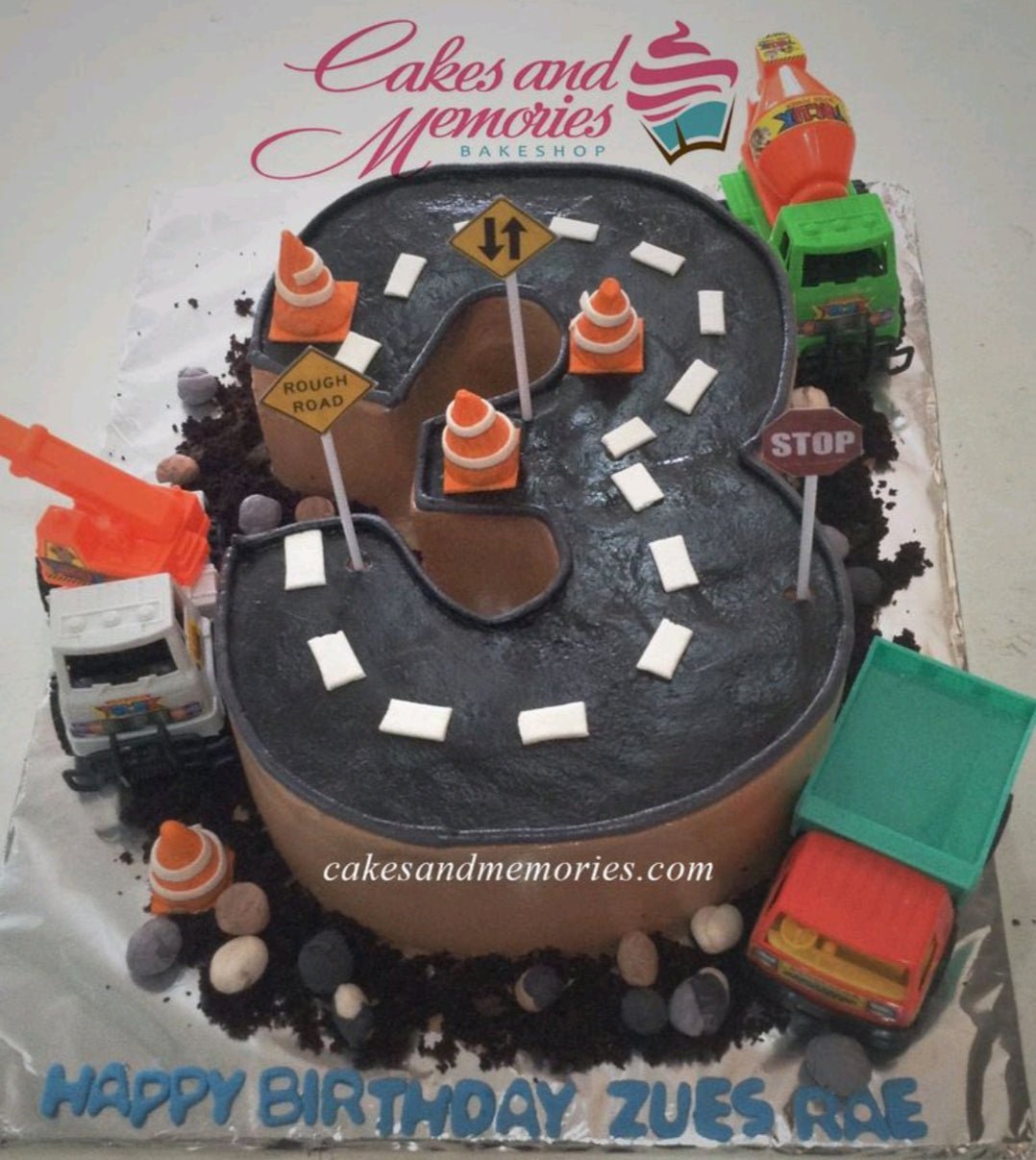 Number 3 shaped construction themed cake with road icing, toy trucks, and traffic sign toppers. Number 3 shaped construction themed cake with road icing, toy trucks, and traffic sign toppers.