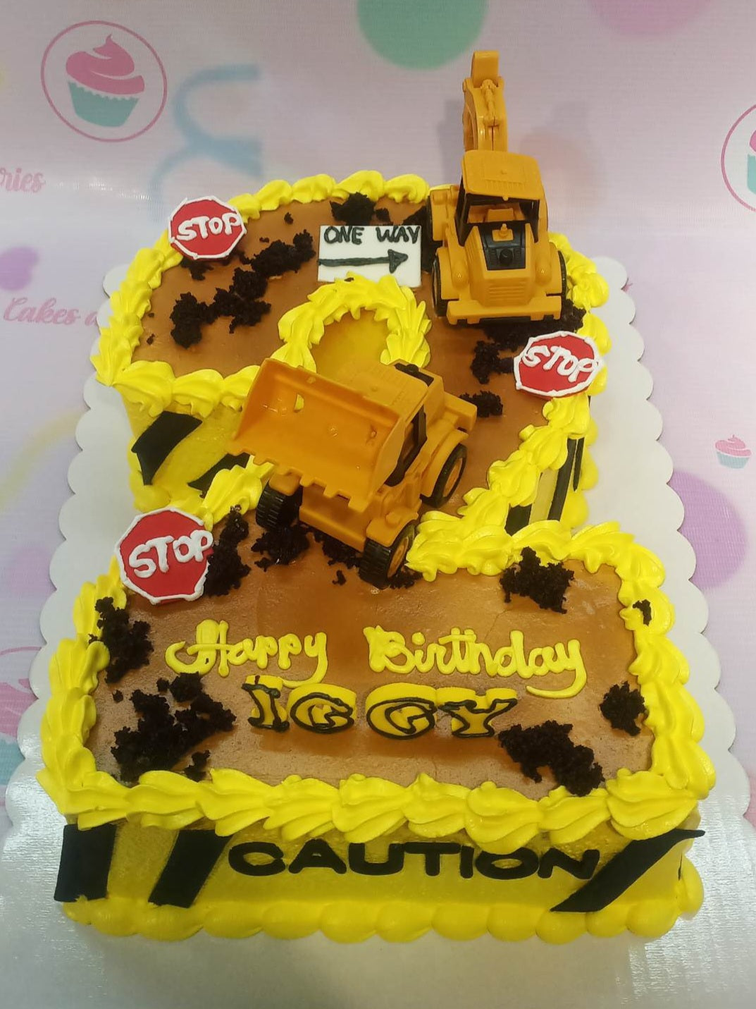 Construction themed number 8 shaped cake with yellow icing, toy excavators, stop signs, and chocolate soil accents. Construction themed number 8 shaped cake with yellow icing, toy excavators, stop signs, and chocolate soil accents.