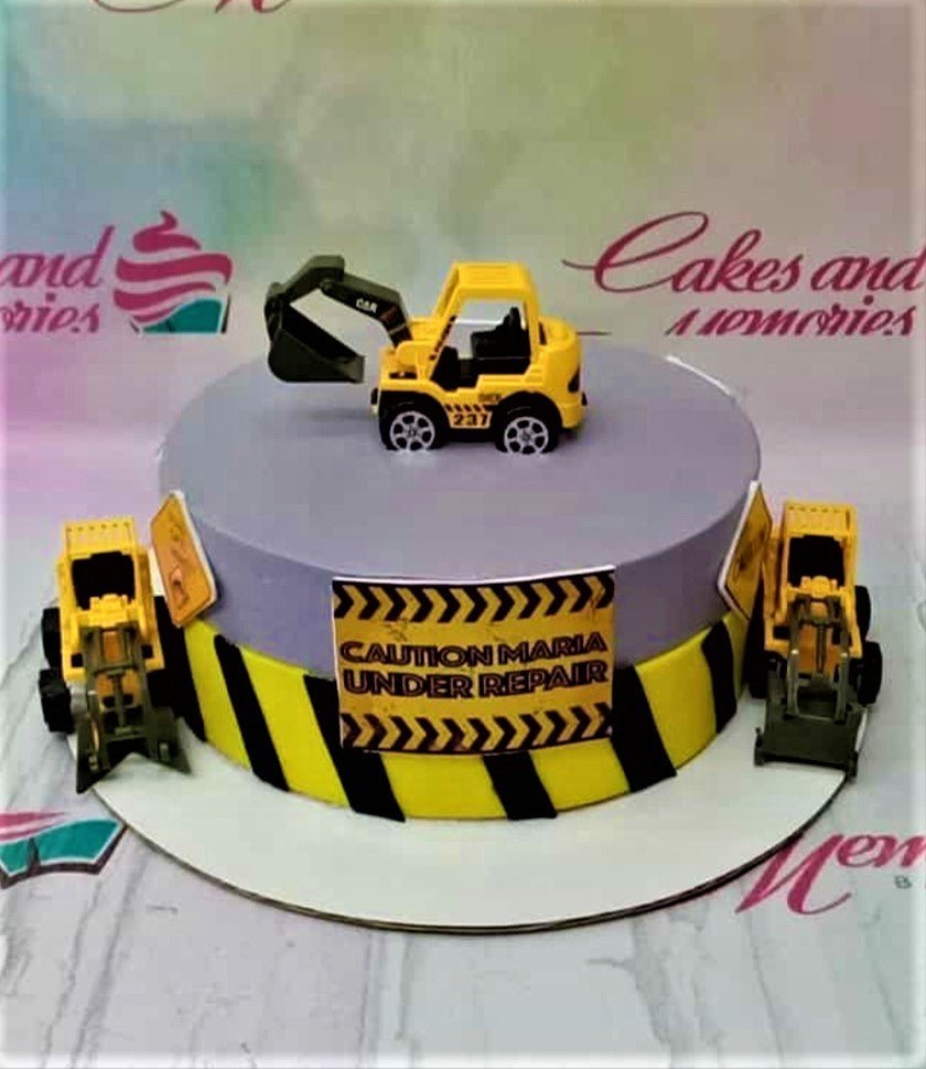 Construction themed birthday cake with yellow toy excavators and a caution sign message on a purple and yellow striped base. Construction themed birthday cake with yellow toy excavators and a caution sign message on a purple and yellow striped base.