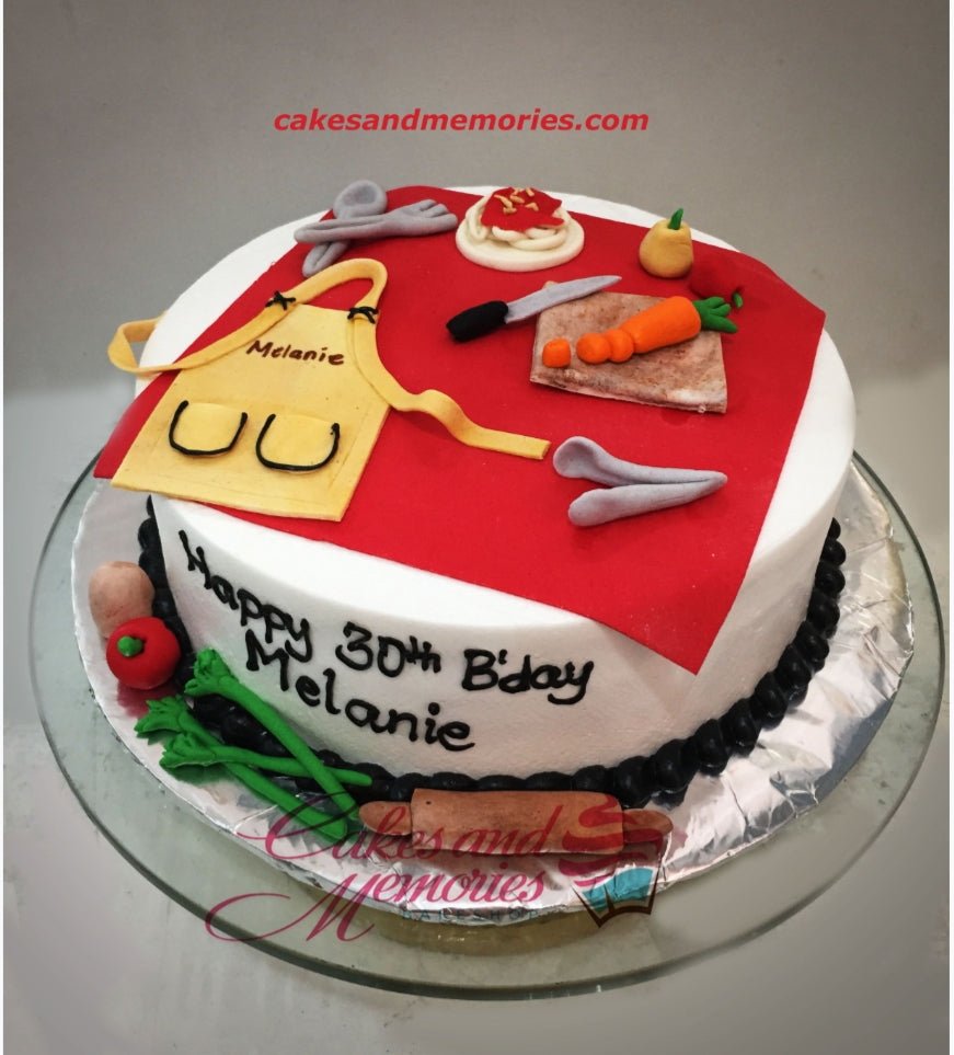 White fondant cake with a red apron topper, cooking utensils, and vegetables for a 30th birthday celebration. White fondant cake with a red apron topper, cooking utensils, and vegetables for a 30th birthday celebration.