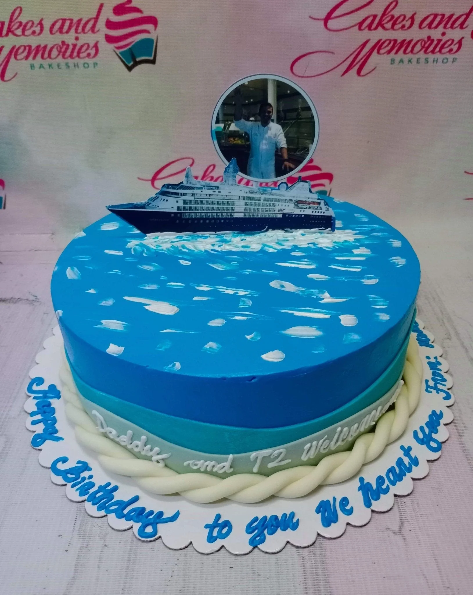 Cruise Ship Sky Blue Cake A blue ocean-themed 1-tier cake with a cruise ship printout, a circular photo topper, white icing waves, and a white fondant rope border.