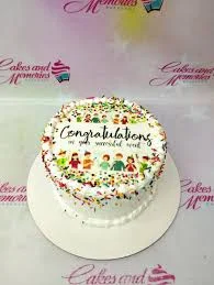 A white and colorful 1-tier cake themed for congratulations, featuring a circular printout with cartoon people and colorful sprinkles.