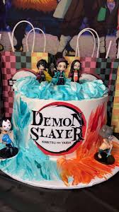Demon Slayer themed cake with anime character figurines and blue and orange textured icing Demon Slayer themed cake with anime character figurines and blue and orange textured icing