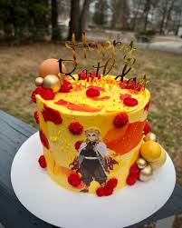 A multicolor buttercream cake featuring a Kyojuro Rengoku character printout, a gold Happy Birthday topper, gold and peach spheres, red icing dollops and gold sugar beads. A multicolor buttercream cake featuring a Kyojuro Rengoku character printout, a gold Happy Birthday topper, gold and peach spheres, red icing dollops and gold sugar beads.