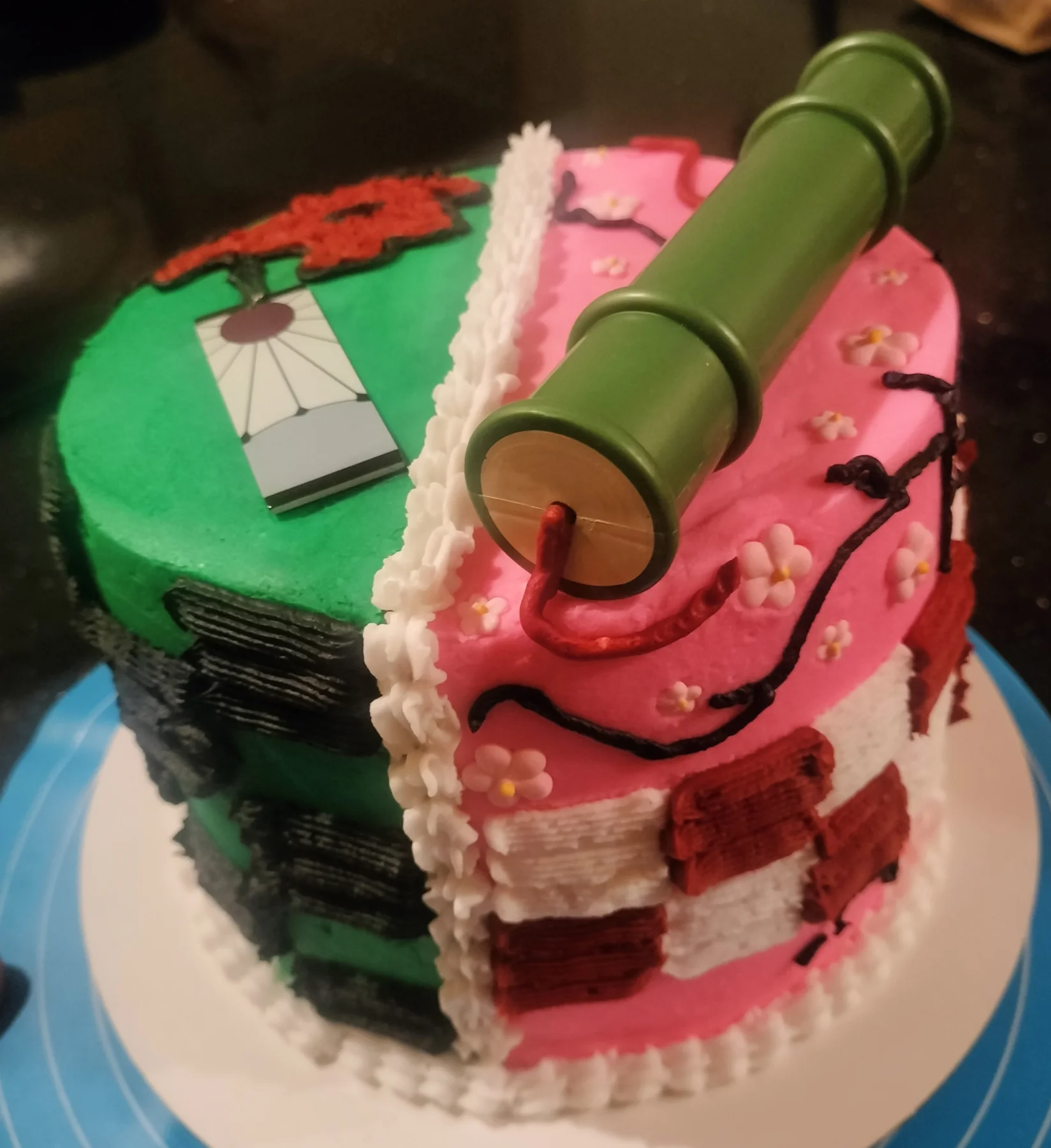 A green 1 tier cake featuring a bamboo muzzle prop, a hanafuda earring design printout, pink cherry blossoms, black branches and checkered patterns. A green 1 tier cake featuring a bamboo muzzle prop, a hanafuda earring design printout, pink cherry blossoms, black branches and checkered patterns.