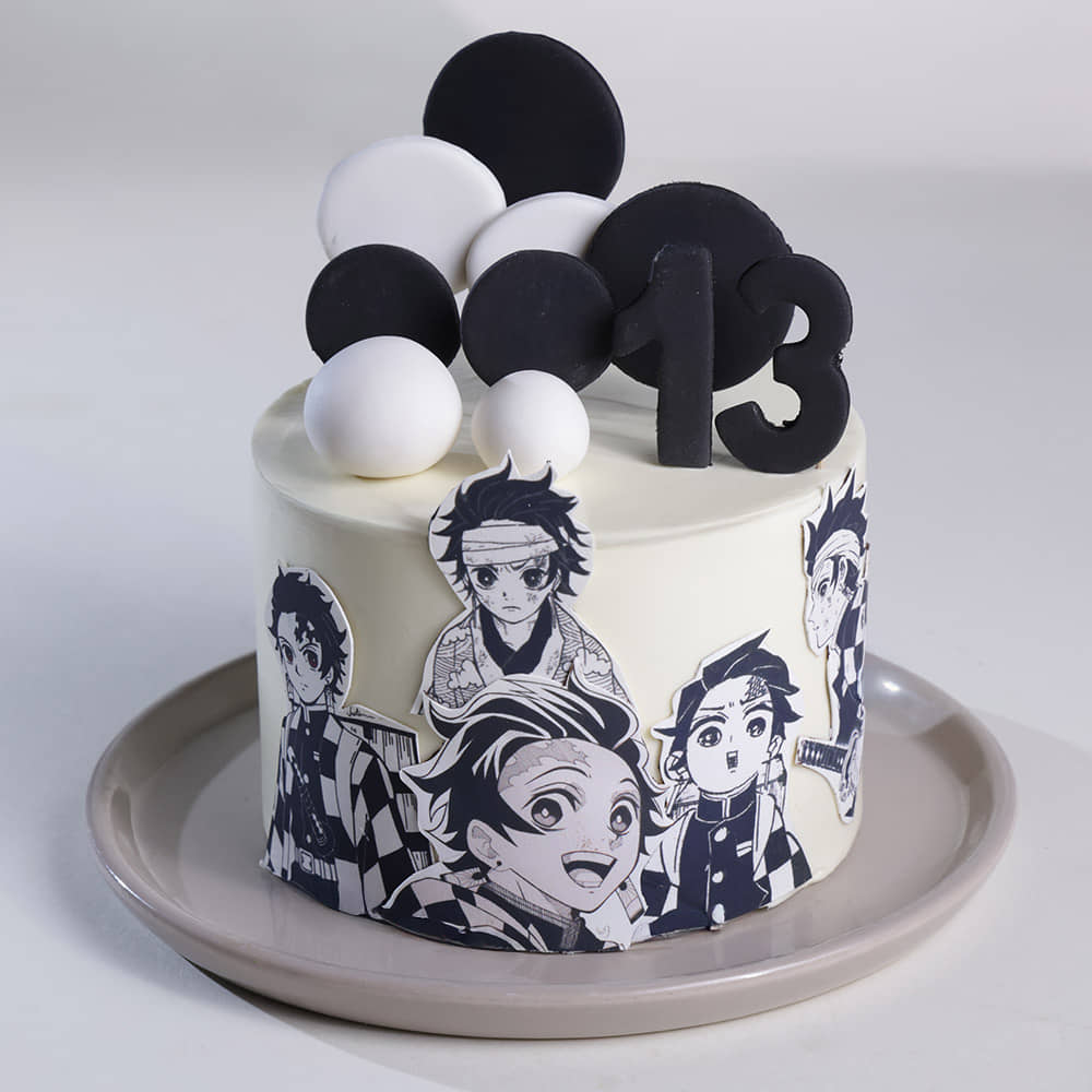 A white 1 tier cake featuring a black number 13, character cutouts of Tanjiro Kamado, black circular discs, and white fondant discs and spheres. A white 1 tier cake featuring a black number 13, character cutouts of Tanjiro Kamado, black circular discs, and white fondant discs and spheres.