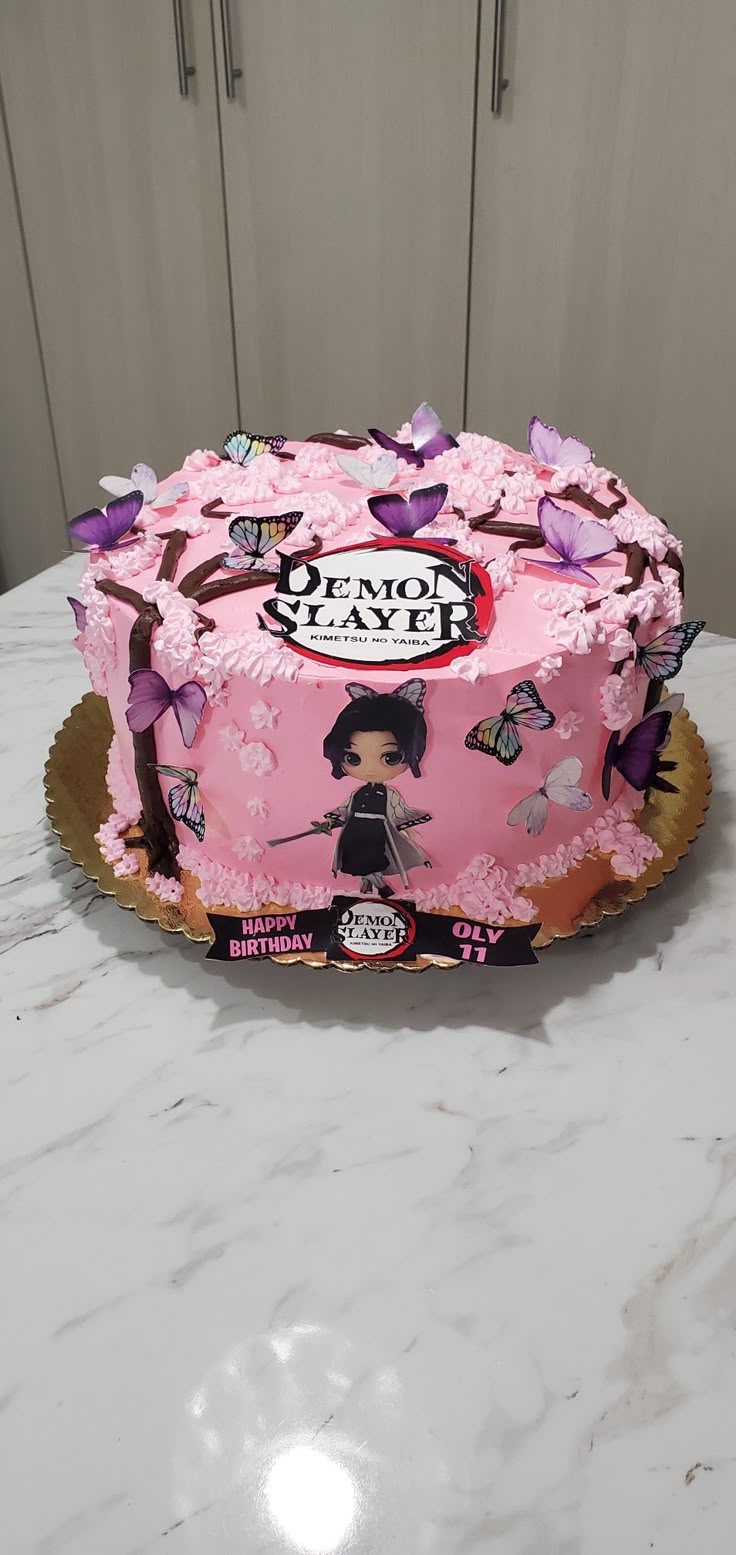 A pink 1 Tier cake featuring Demon Slayer logo and character printouts, butterfly decorations, cherry blossom piping, and tree branch icing. A pink 1 Tier cake featuring Demon Slayer logo and character printouts, butterfly decorations, cherry blossom piping, and tree branch icing.