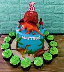 Blue dinosaur birthday cake with a red volcano topper and various dinosaur figurines