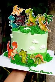 Light green dinosaur cake with printed dinosaur toppers, fondant grass, and white clouds