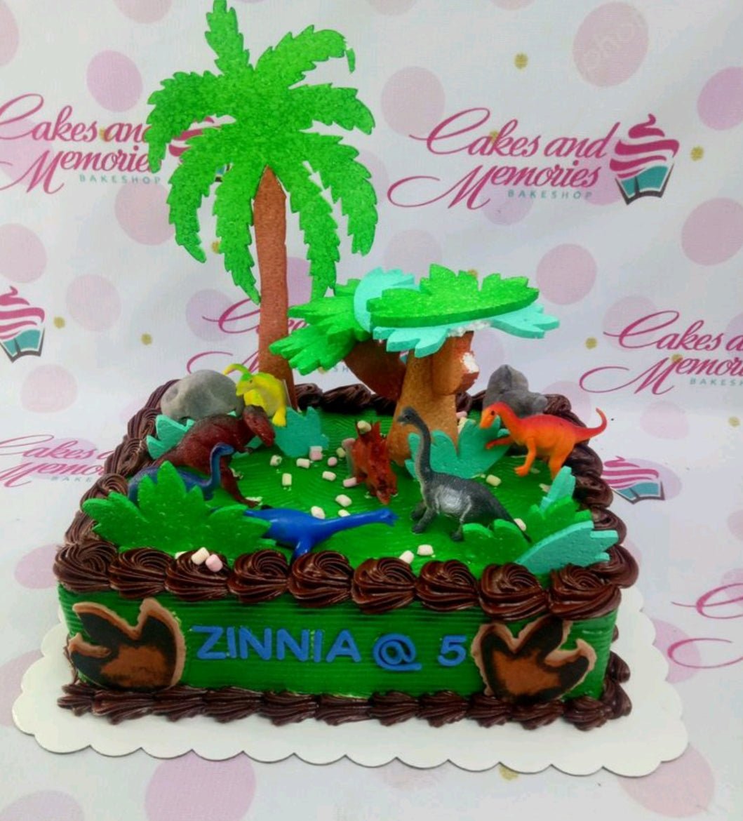 Green dinosaur themed rectangle cake with chocolate icing borders and plastic dinosaur toys on a grassy field design. Green dinosaur themed rectangle cake with chocolate icing borders and plastic dinosaur toys on a grassy field design.