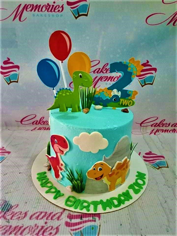 Light blue dinosaur themed birthday cake with colorful balloon and dinosaur printouts and a large number 2 topper. Light blue dinosaur themed birthday cake with colorful balloon and dinosaur printouts and a large number 2 topper.