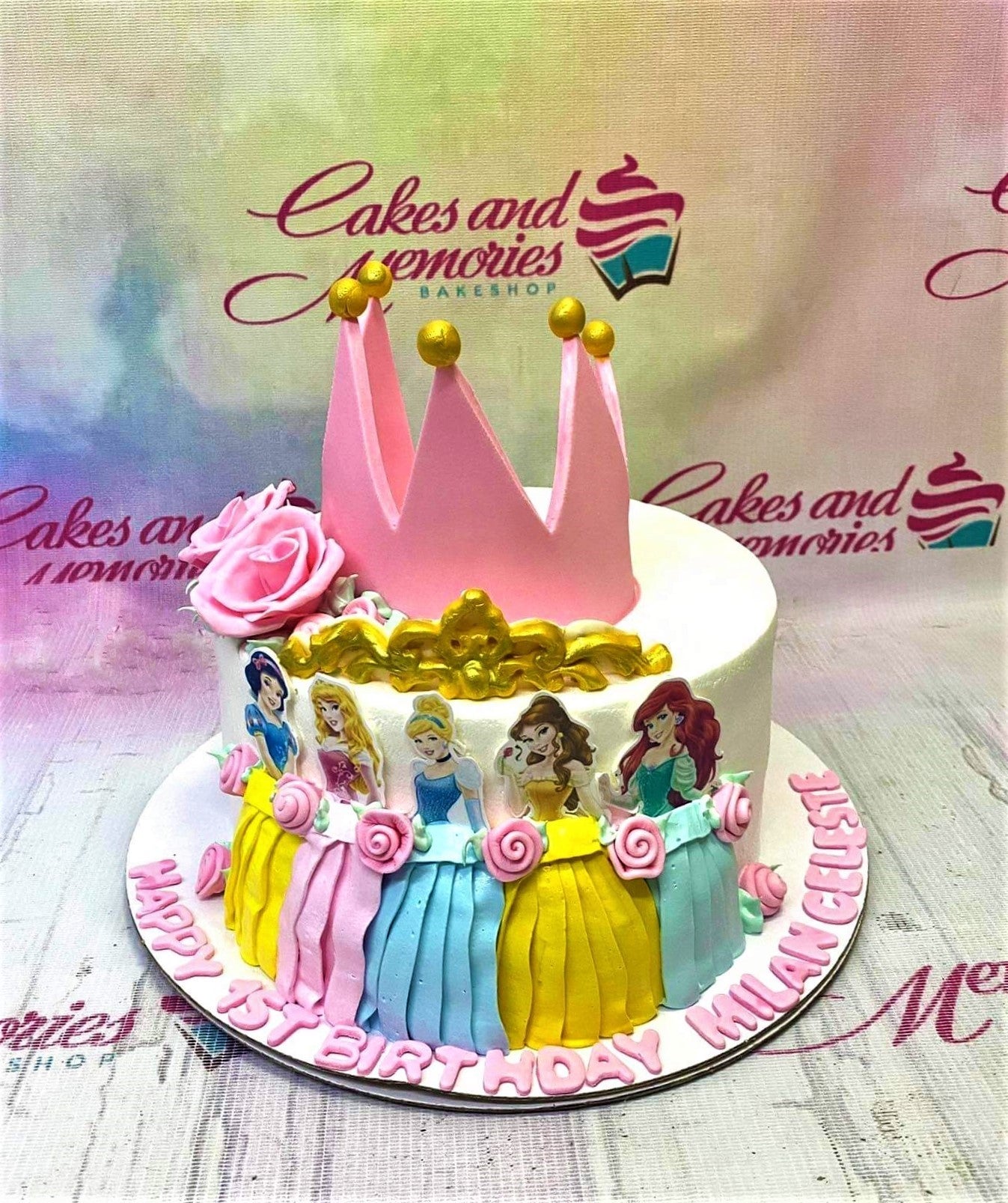 Disney Princess themed birthday cake with a large pink fondant crown, gold tiara, and printed princess characters on the side. Disney Princess themed birthday cake with a large pink fondant crown, gold tiara, and printed princess characters on the side.