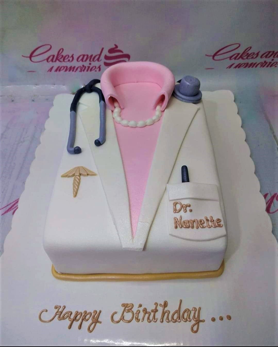 White and pink doctor's coat fondant cake with a stethoscope, pearl necklace, and medical caduceus symbol. White and pink doctor's coat fondant cake with a stethoscope, pearl necklace, and medical caduceus symbol.