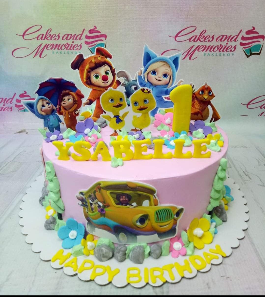 Pink 1-tier birthday cake with yellow ducks and character printouts, featuring a yellow number 1 topper and gumpaste letters. Pink 1-tier birthday cake with yellow ducks and character printouts, featuring a yellow number 1 topper and gumpaste letters.