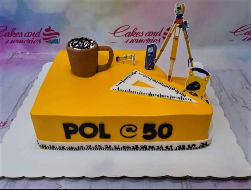 Yellow square cake for a 50th birthday featuring engineering and surveying tools like a tripod, ruler, and a 3D fondant coffee mug. Yellow square cake for a 50th birthday featuring engineering and surveying tools like a tripod, ruler, and a 3D fondant coffee mug.