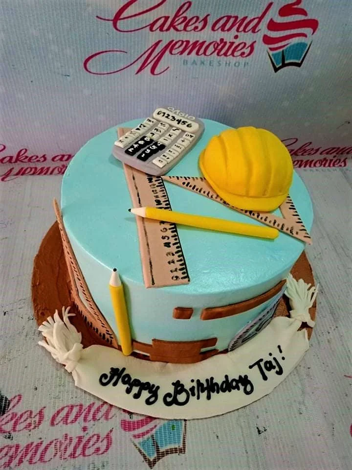 Light blue engineering themed cake with yellow hard hat, calculator, ruler, and pencil fondant toppers.