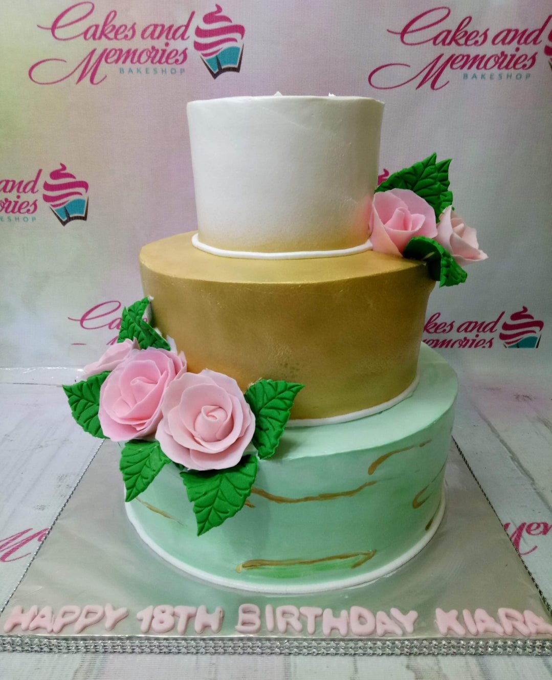 Elegant 3-tier birthday cake with white, gold, and mint green tiers decorated with pink gumpaste roses and green leaves. Elegant 3-tier birthday cake with white, gold, and mint green tiers decorated with pink gumpaste roses and green leaves.