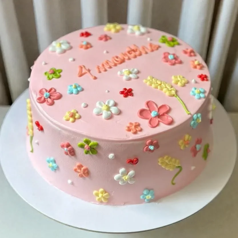 Floral Minimalist Pink Cake Pink minimalist cake decorated with colorful piped icing flowers and '4 months' message.